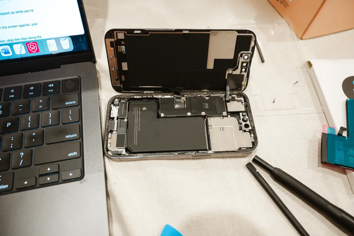 使用工具與筆電開啟iPhone，展示DIY電池更換過程。
