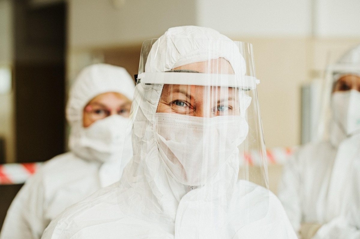 trabalhadores em roupas de proteção em uma fábrica de baterias