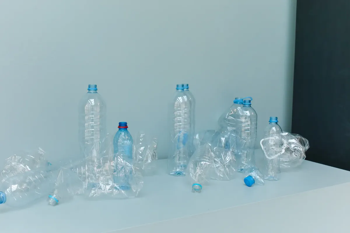 白い表面に空のプラスチックボトルが置かれたミニマリストックの静物で、環境意識を促進しています。