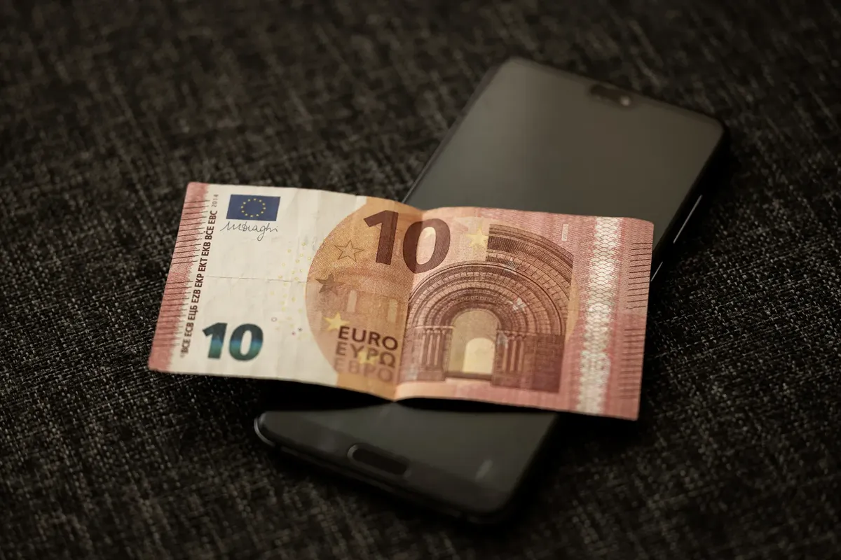 10ユーロ通貨がスマートフォンに置かれたクローズアップ写真、通貨とデジタル技術を強調している。