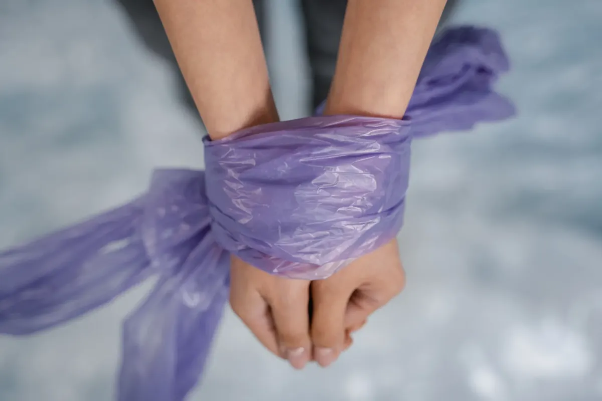 Hands bound with purple plastic in a close-up view conveying restriction and bondage.