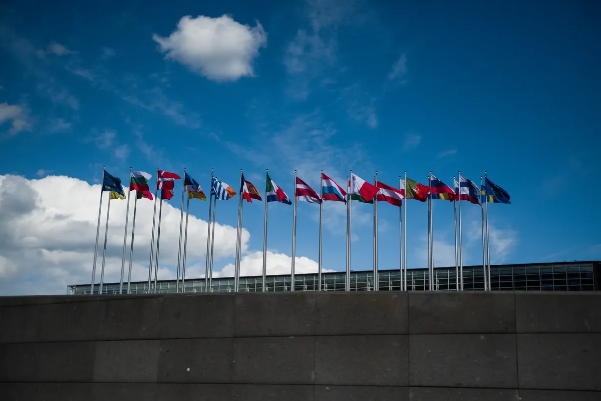 Row of European flags fluttering against a clear blue sky, symbolizing unity.